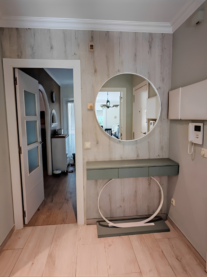Recibidor reformado con espejo circular y mueble suspendido